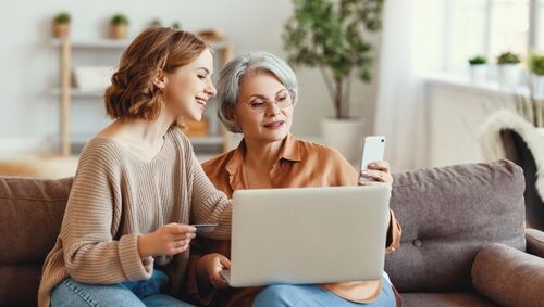 Enkelin hilft Seniorin beim Internet-Shopping