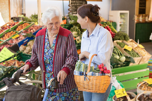 Frau hilft Seniorin mit Rollator beim Einkaufen